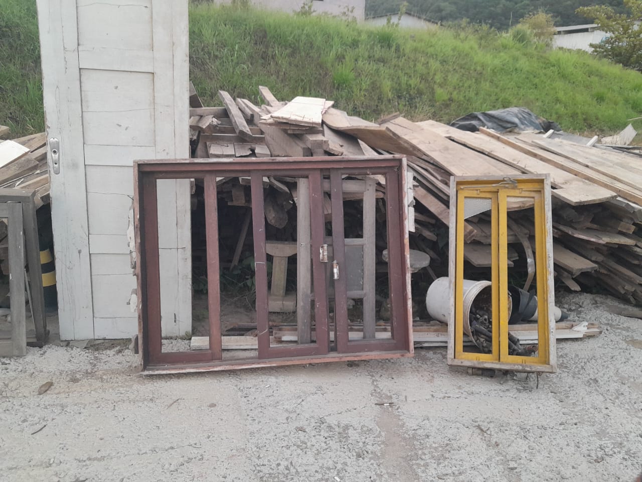 Estoque de materiais de construção reaproveitados: portas, janelas e tábuas de madeira recuperados e prontos para reuso.