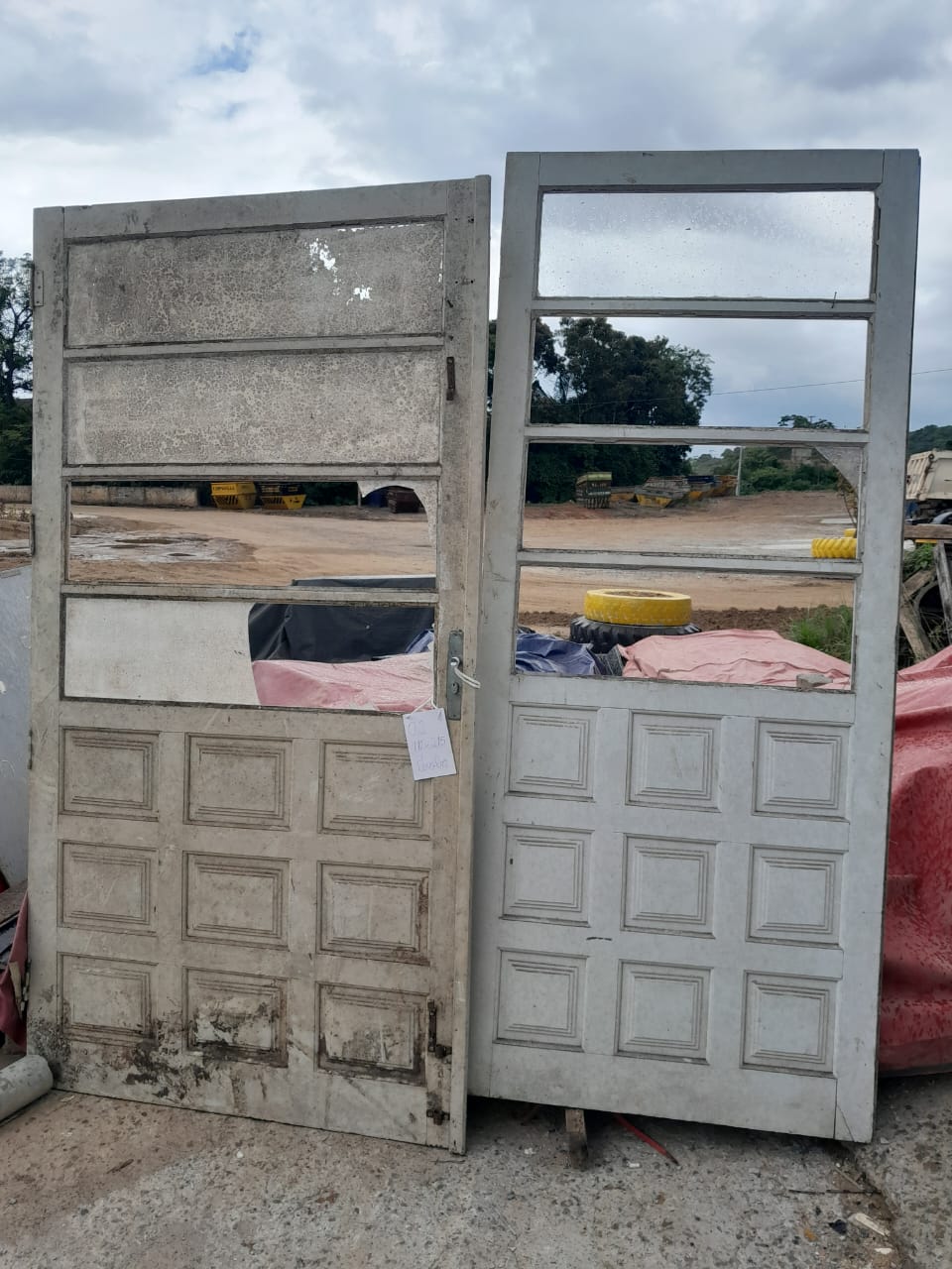 Duas portas de madeira reaproveitadas com vidros, em estoque no pátio da empresa para venda