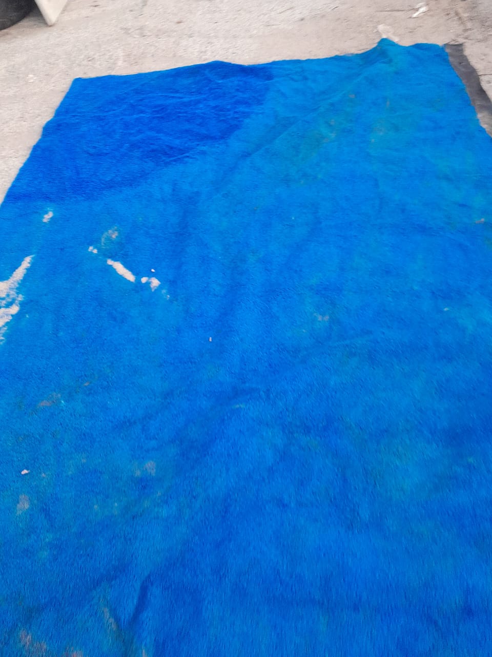Lona azul usada em obra/construção, disposta no chão, exemplificando material disponível para venda ou reutilização.